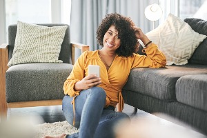 Woman sitting on floor in living room with cell phone